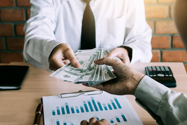 Businessman give dollar bills to partner.